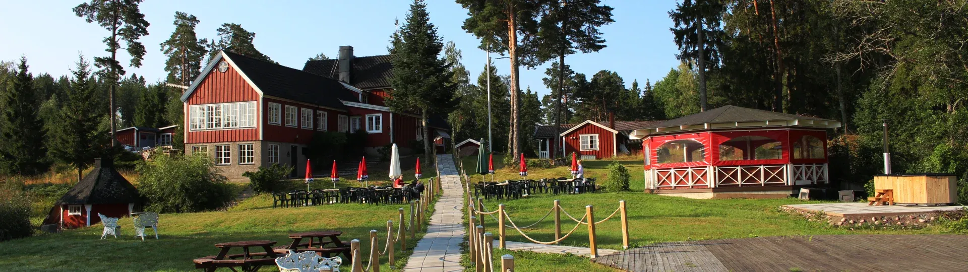 Odalgårdens byggnader och öppna gräsmattor en sommardag.