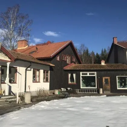 Gårdens huvudbyggnad i snö med röda tegeltak.