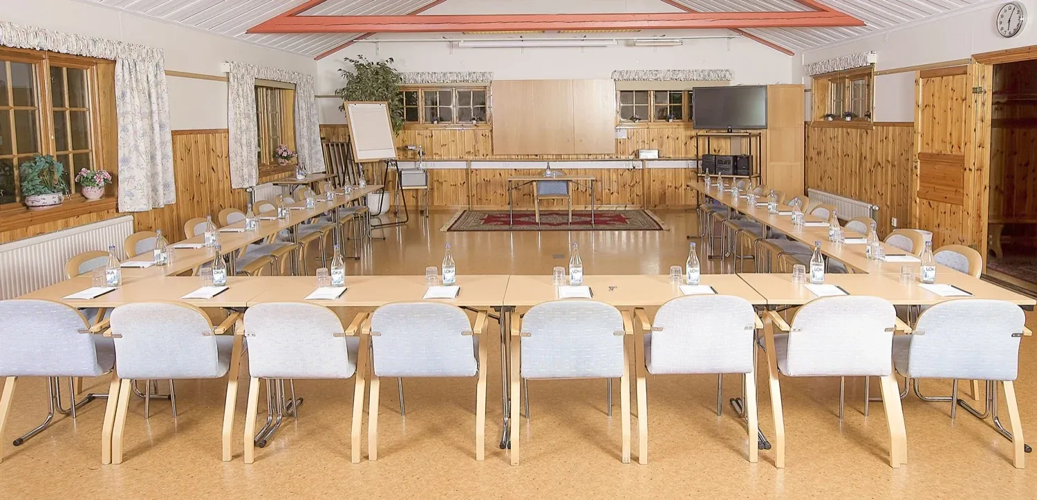 Lång konferensuppställning med bord i rad och trägolv.