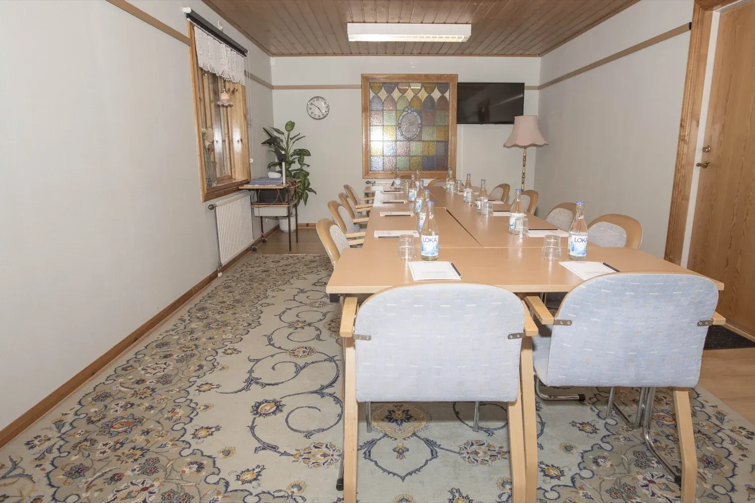 Mindre konferensrum med bord för en liten grupp och fönster mot grönskan.
