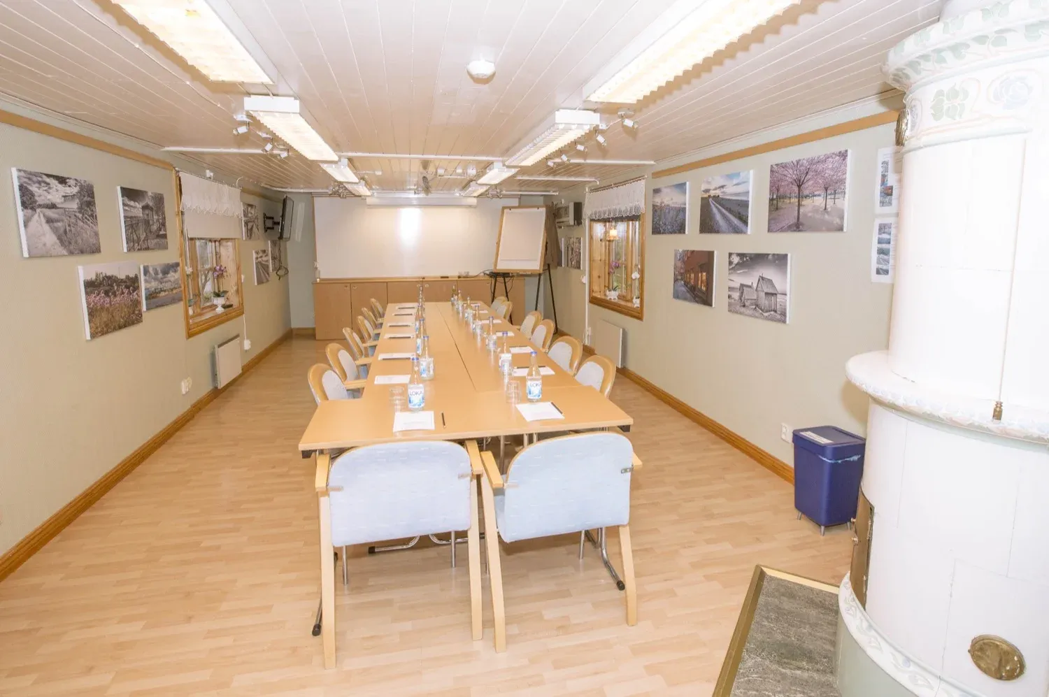 Konferensrum med bord i U-form, tavlor på väggarna och vitmålad panel.
