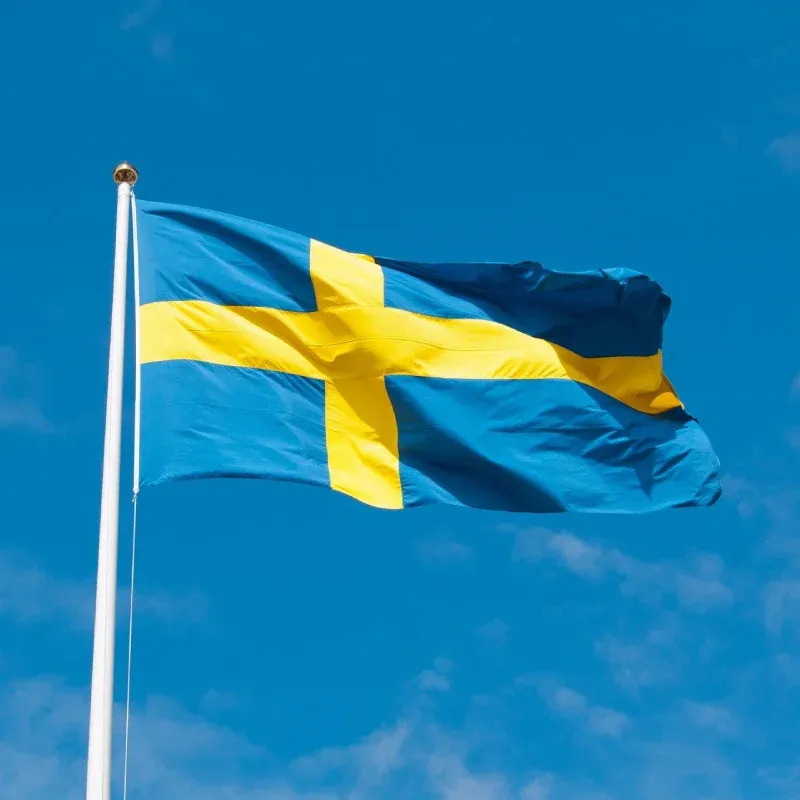 Den svenska flaggan som vajar mot en klarblå himmel.