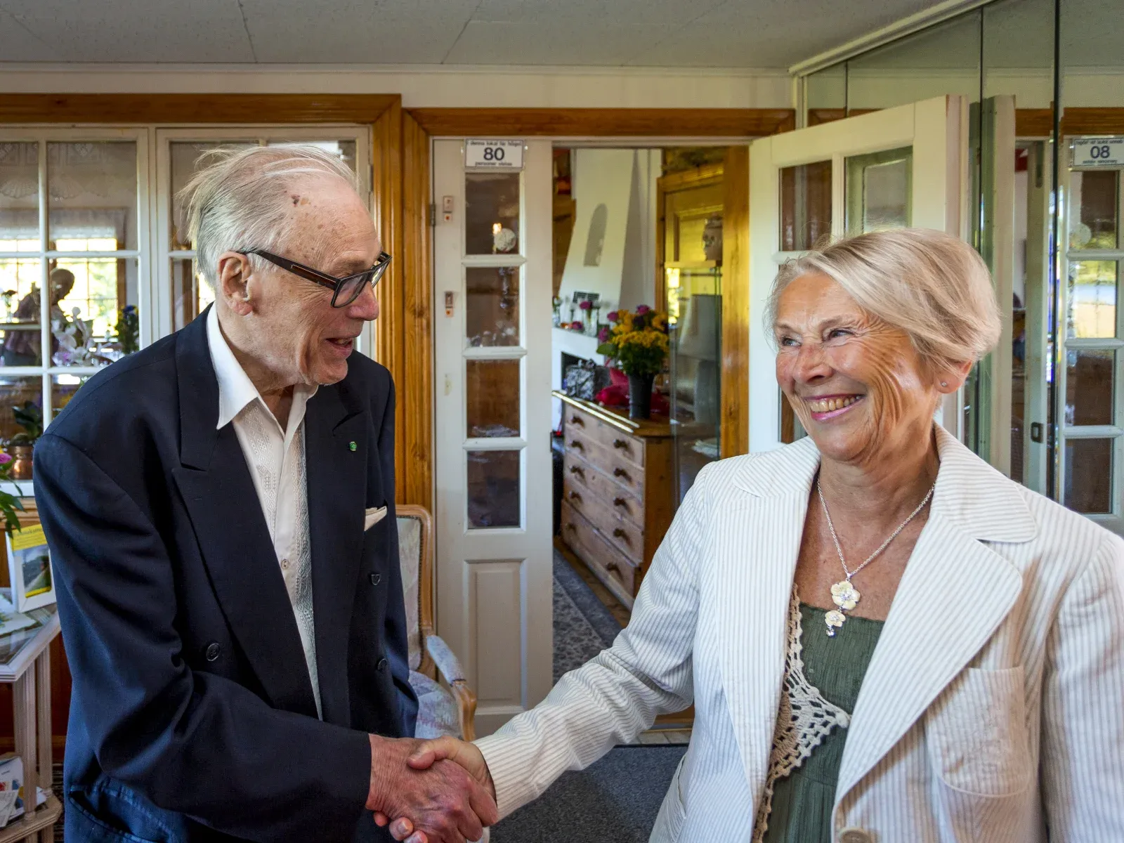 Två gäster som hälsar på varandra med handslag i entrén.